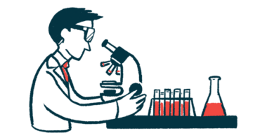 A scientist uses a microscope with a row of test tubes nearby.